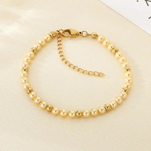 Close-up of elegant gold beads and light gold pearls bracelet on beige fabric