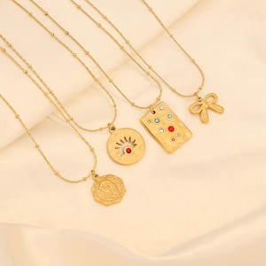 Four gold layered necklaces with coin and tarot pendants on beige silk background