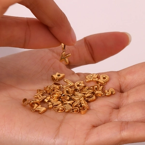 Macro shot of 18K gold-plated mini letter charms held by hand for DIY jewelry making