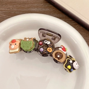 Detail of bear and donut charms on a brown translucent hair claw clip in a white dish