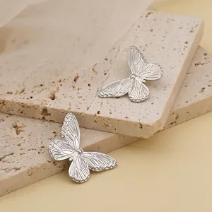Detailed close-up of butterfly stud earrings in silver finish on stone display