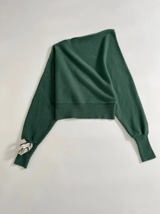 Detail of dark green knit top featuring ribbed cuffs and unique silver metal accent