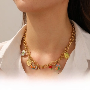 Detailed shot of gold chain necklace with colorful enamel butterfly and floral pendants