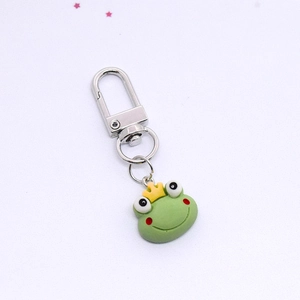 Detailed view of a cute resin green frog prince keychain with yellow crown and silver clasp