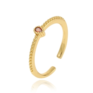 Minimalist gold teardrop ring with red gemstone and beaded texture on white background
