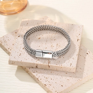 Detailed close-up of a silver stainless steel braided bracelet with a magnetic clasp on stone