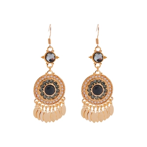 Boucles d'oreilles bohèmes dorées avec glands, pierres sombres, perles et strass sur fond blanc