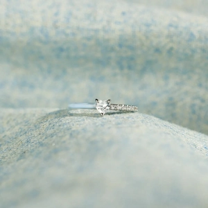 Macro shot of silver heart cut gemstone ring with pavé diamonds on blue knit fabric