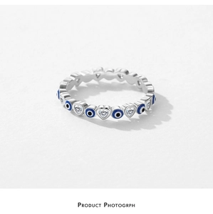 Detailed view of silver ring featuring heart zircons and blue enamel evil eye charms