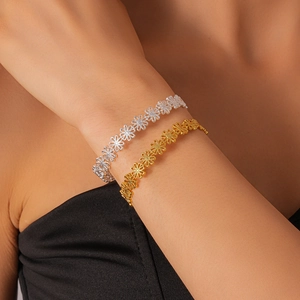 Detail view of gold and silver cutout daisy flower bracelets on a model wrist