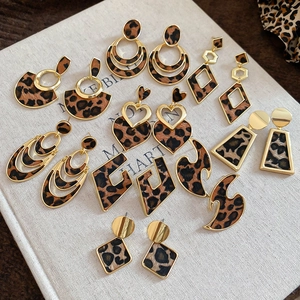 Detailed close-up of leopard print geometric earrings set on vintage textured book