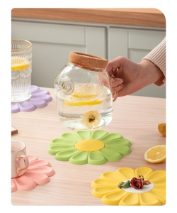 Close-up of heat-resistant silicone daisy coasters in assorted pastel colors on a table