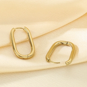 Minimalist gold oval U-shaped hoop earrings displayed on elegant beige silk fabric