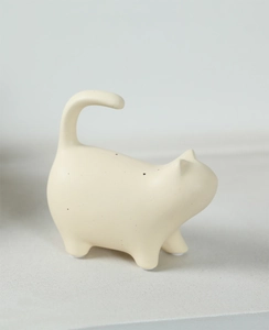 Close-up of minimalist cream ceramic cat statue with fine black speckles and matte finish
