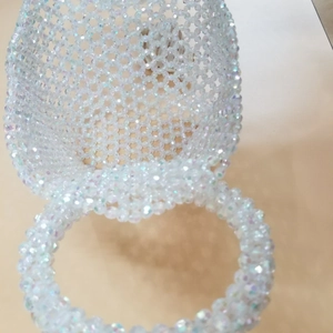 Detailed view of handmade iridescent acrylic bead weaving and circular handle of handbag