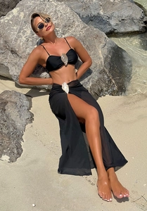 Detail of black beach cover-up skirt and bikini top with silver metal seashell buckles