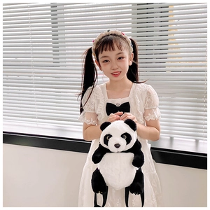 Detailed view of the plush panda backpack worn by a child in white lace dress