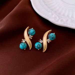 Detailed shot of vintage gold earrings with turquoise beads and crystals on brown silk