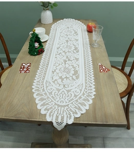 Close-up of white lace table runner with floral patterns and scalloped edges for Christmas