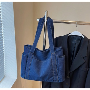 Detail of dark blue denim tote bag with yellow stitching and spacious side pocket design