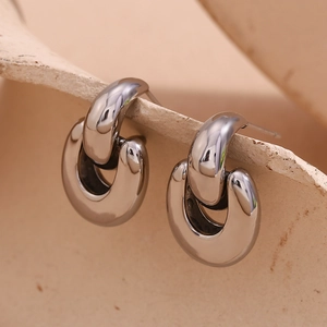 Close-up of geometric intertwined U-shaped polished silver stud earrings in minimalist style