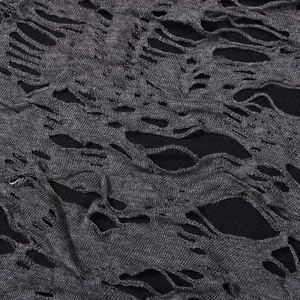 Macro detail of dark grey distressed knit fabric showing ripped hollow texture on dress