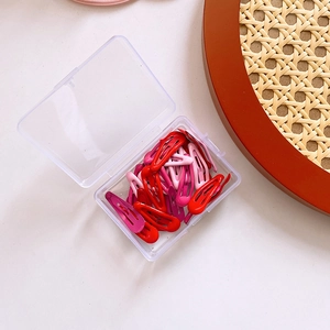 Close-up of colorful candy-colored metal BB clips in a clear plastic storage box