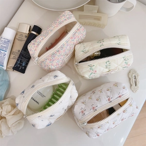 Détail de trousses à maquillage matelassées à fleurs avec fermeture éclair et texture douce