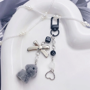 Cute plush puppy bag charm with black bow and heart beads on a white heart ceramic tray