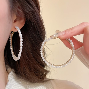 Detailed view of large gold hoop earring with small white pearls on model for vintage look