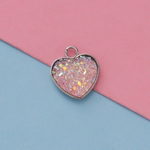 Macro shot of 13mm heart-shaped pink resin pendant with silver metal bezel and glitter