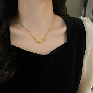 Primo piano della collana minimalista in oro con sei perline indossata sul collo