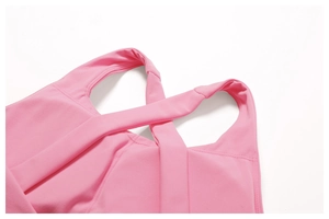 Dettaglio del reggiseno sportivo rosa ad alto impatto con spalline incrociate e cuciture fini