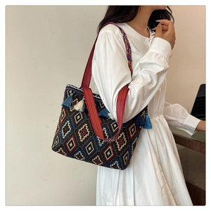 Ethnic shoulder bag with geometric patterns and tassels worn with a white dress