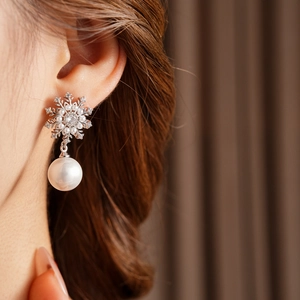 Détail des boucles d'oreilles vintage flocon de neige et perles portées par un mannequin