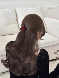 Detailed view of a small red rose hair claw clip on brunette hair for a half-up style