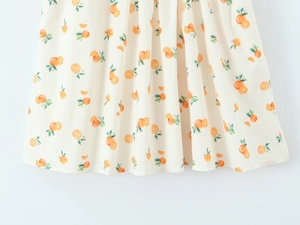 Detailed close-up of cream lace dress hem with fresh orange fruit patterns and soft pleats