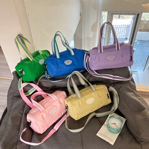 Five colorful cylinder sports bags for kids gymnastics and dance on a grey sofa