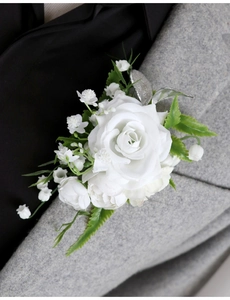 Close-up of white artificial rose boutonniere pinned on a dark grey wool suit lapel
