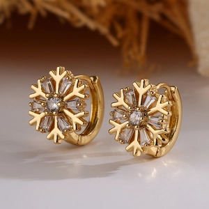 Exquisite gold snowflake huggie earrings with sparkling cubic zirconia on a natural background