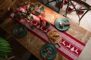 Detail of red knitted Christmas table runner with white reindeer and snowflake jacquard patterns