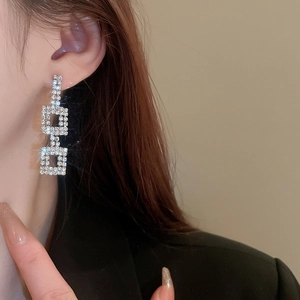 Detail of silver square geometric earring with rhinestones on model's ear