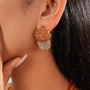Macro detail of acorn leaf earring with orange and champagne crystals in golden alloy