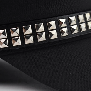 Black beret hat with silver square metal studs on leather strap in a close-up side view