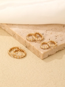 Macro shot of three pairs of gold-plated hoop earrings with micro-set cubic zirconia details