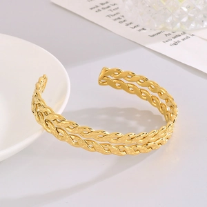 Detailed view of the golden double-layered woven texture on a stainless steel open bangle