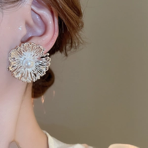 Close-up of floral pearl stud earring with silver metal texture on a female model