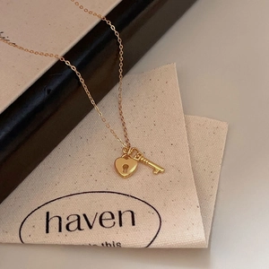 Close-up of a 925 sterling silver heart lock and key pendant on a gold link chain