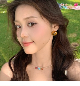 Outdoor close-up of amber resin earrings and rainbow heart necklace on a model