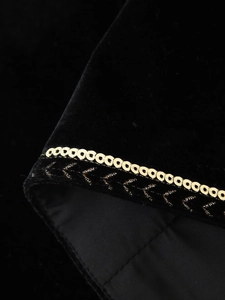 Detail of black velvet vest featuring golden metal rings and intricate braided embroidery